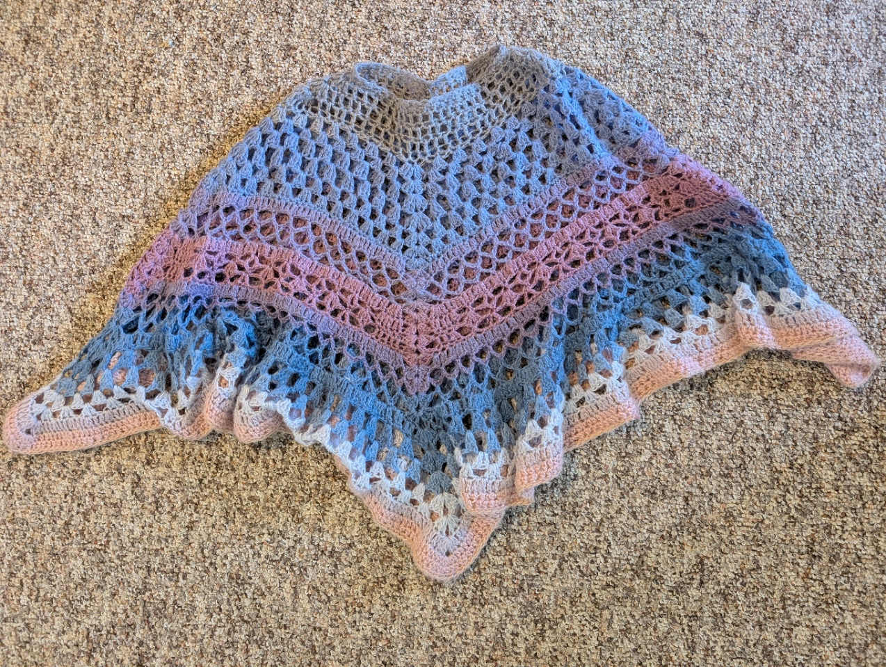 It is an airy poncho that changes colour through the pieces, starting with a strip of gray and then mixing between purples, pinks and blues. 